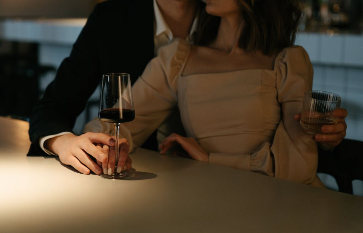 Ein Paar genießt ein romantisches Date in einer stilvollen Bar mit einem Glas Wein und einem Cocktail in der Hand, ideal für ein unvergessliches Erlebnis mit einem Escort in Köln.
